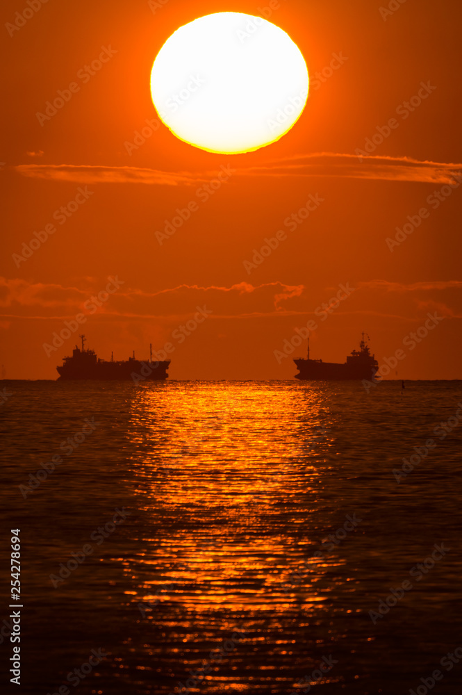 昇る朝日と海を渡る船の影