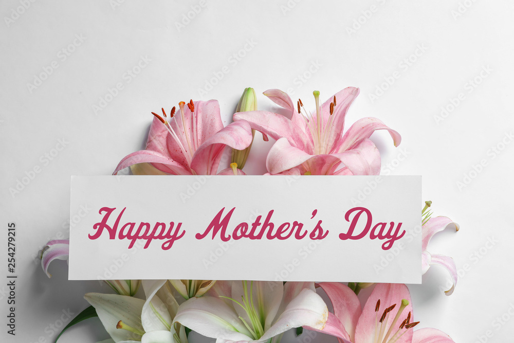 Composition with beautiful blooming lily flowers and card on white background