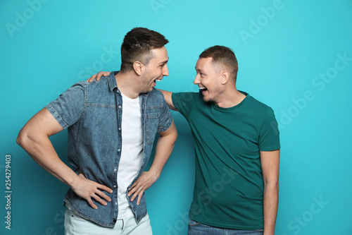 Man laughing with his friend against color background photo