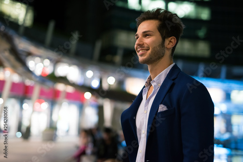 Smiling young man walking outdoors at night