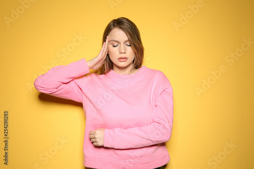 Young woman suffering from headache on color background