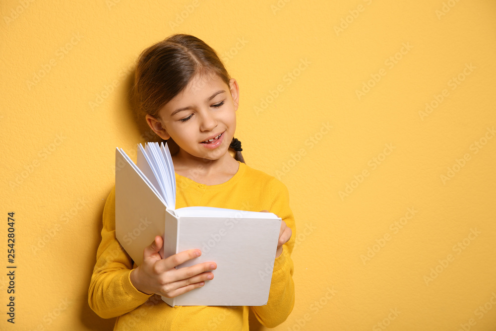Cute little girl reading book on color background, space for text Cute little girl reading book on color background, space for text