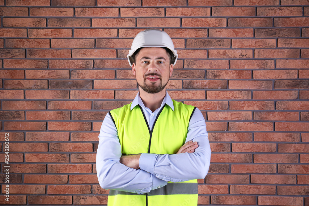 Male industrial engineer in uniform on brick wall background. Safety equipment Male industrial engineer in uniform on brick wall background. Safety equipment