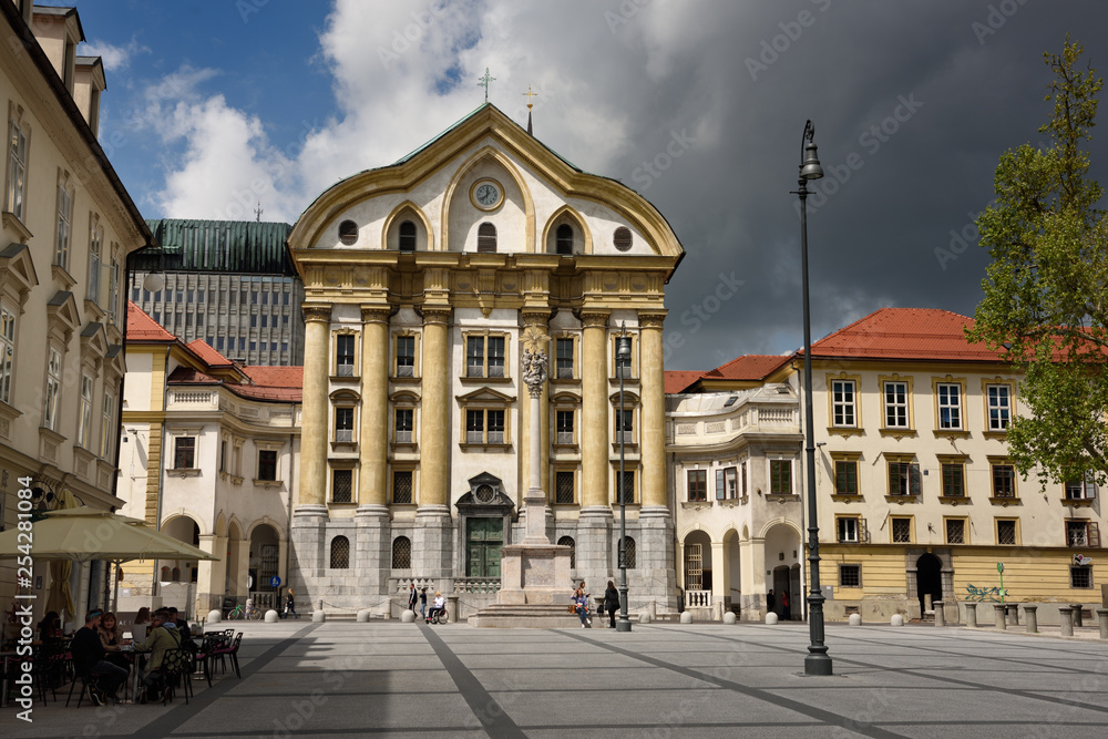 Ursuline Church of the Holy Trinity with marble statues of the Holy Trinity column at Congress Square in Ljubljana Slovenia with dark clouds