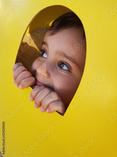 A child looking through a hole, yellow background  © Carmen G. 