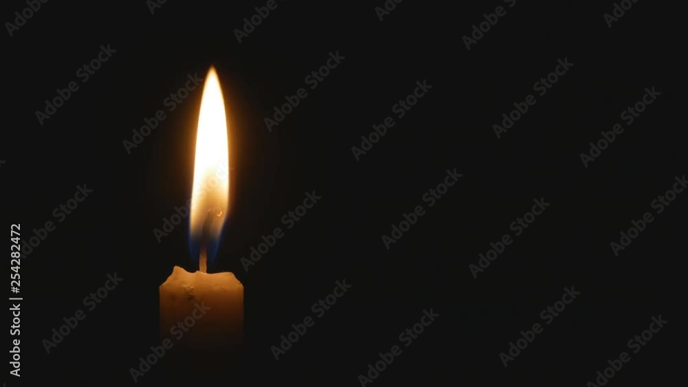The candle burns in the dark. On the left side of the screen The candle burns in the dark. On the left side of the screen
