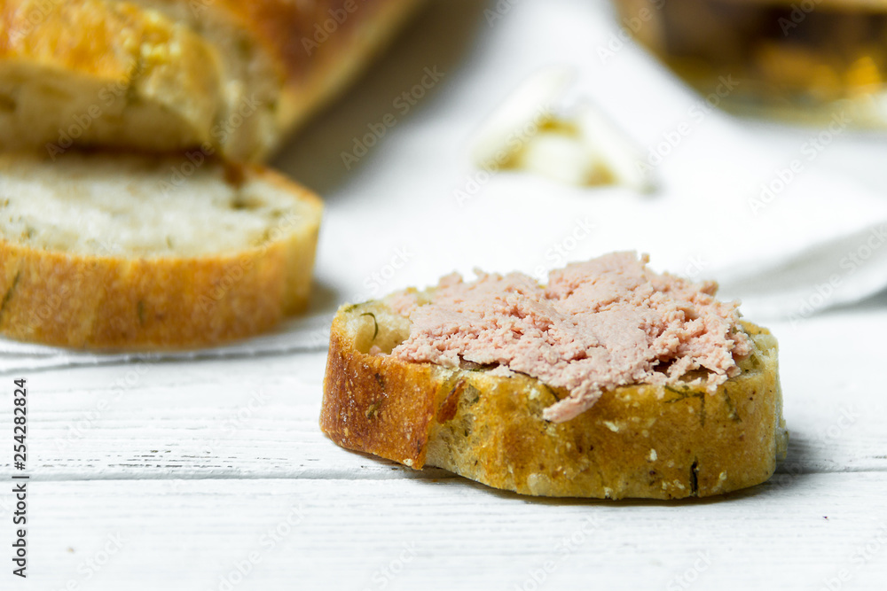 Garlic baguette with pate on white kitchen towel on wooden table.