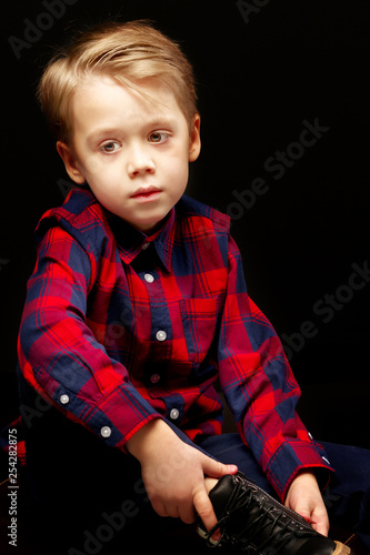 Beautiful little boy on a black background, close-up.