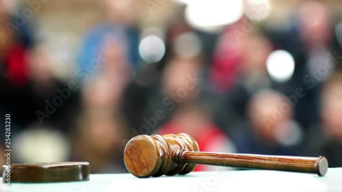 auctioneer or judge gavel mallet in foreground focused with public or jury in background unfocused , HD video footage