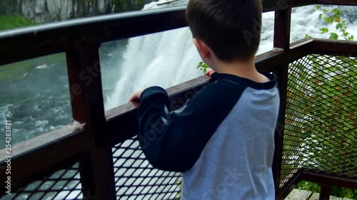 A beautiful slow motion view of Mesa falls in Idaho. A little boy looks at it from an overlook. photo