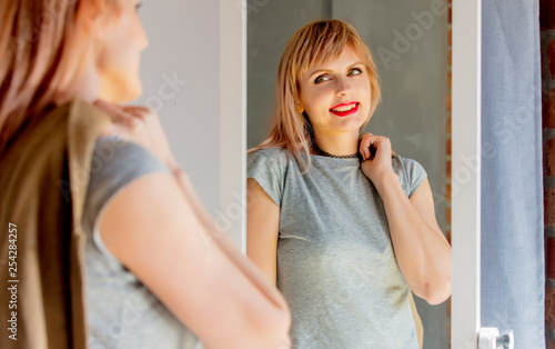woman dressing up near mirror at home.