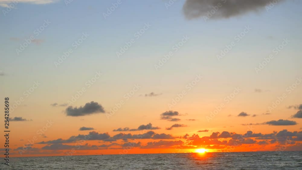 Sun going down on ocean horizon during sunset with a jet ski driving by Sun going down on ocean horizon during sunset with a jet ski driving by