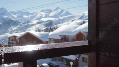 Water droplets falling onto wooden balcony ramp in a ski resort in winter photo