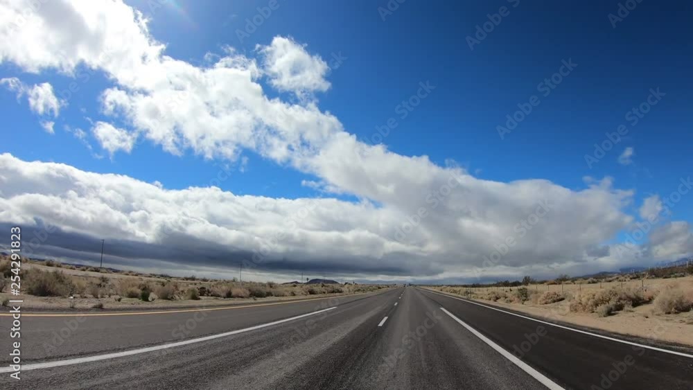 Driving towards the clouds on a long highway in the Mojave Desert Driving towards the clouds on a long highway in the Mojave Desert