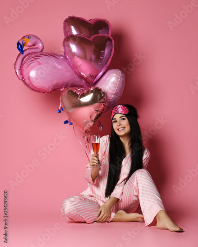 Happy girl holiday party joyful having fun celebrating Valentines Day hold pastel color red and pink air balloons hearts with inflatable flamingo 