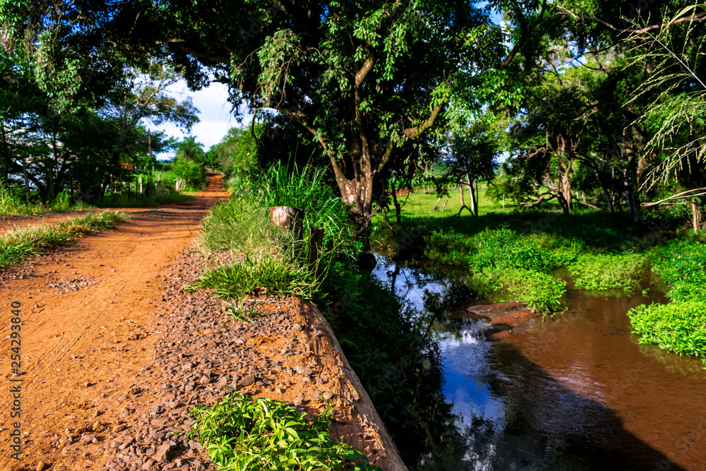 Estrada rural com riozinho ao lado