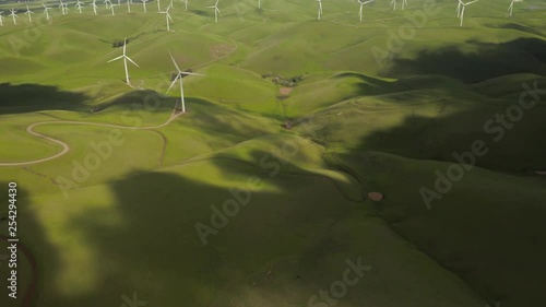 Aerial Shot of clouds rolling on green hills revealing Wind Turbine at Altamont Pass on Vasco Road Highway with green rolling hills in California photo