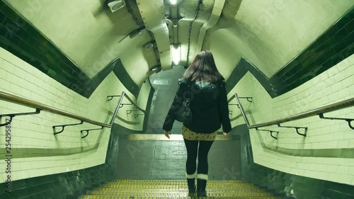 Woman walks alone down the stairs to the London Underground station