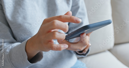 Woman use of mobile phone and sit on sofa at home