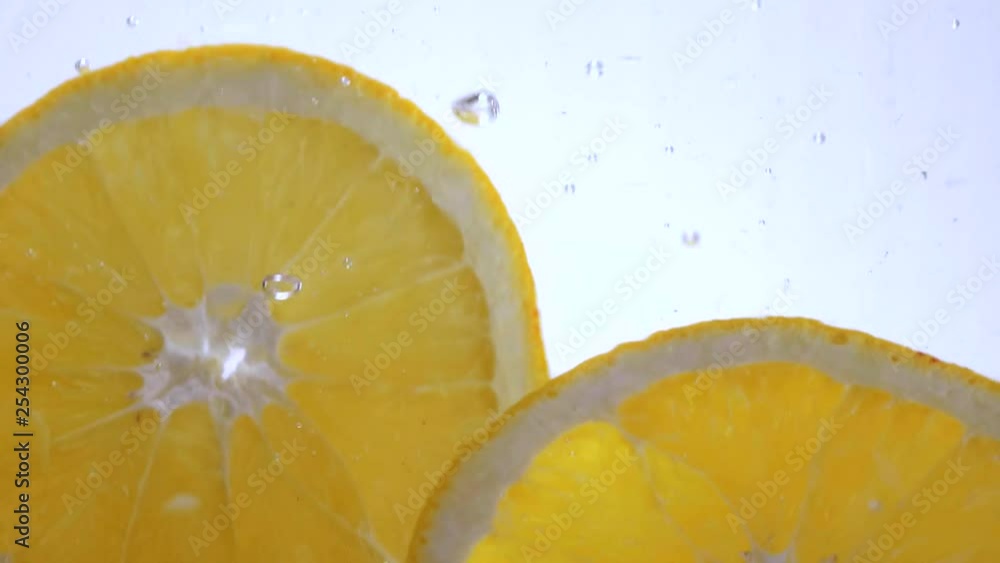 Close up shot of orange slices falling into water Close up shot of orange slices falling into water