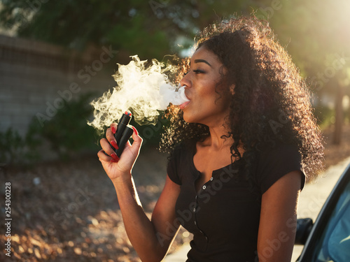 african american woman vaping and exhaling cloud of smoke