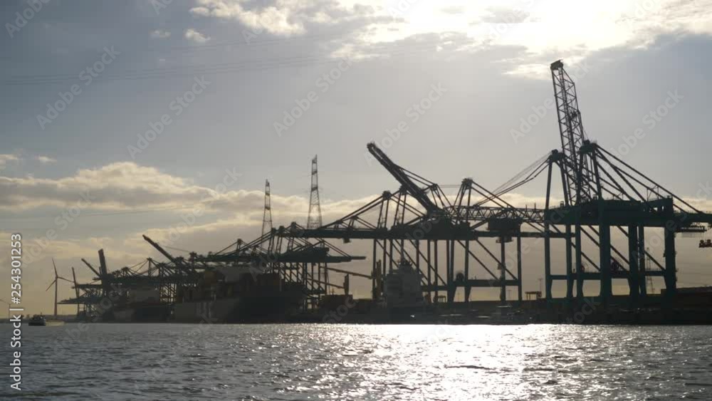View from a boat looking towards huge container port wharf and cranes in Antwerp, Belgium. View from a boat looking towards huge container port wharf and cranes in Antwerp, Belgium.
