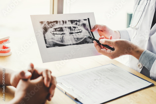 Dentist talking to male patient and presenting results on Dental x-ray film About the problem of the patient in dental office photo