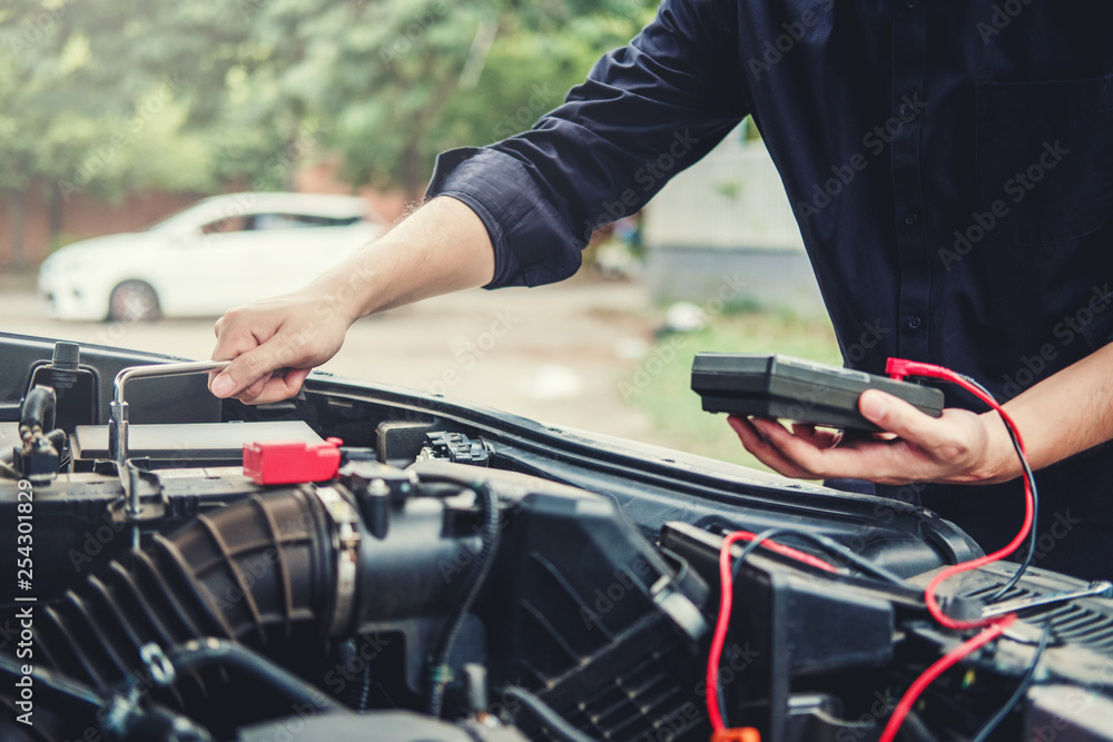 Auto mechanic working in garage Technician Hands of car mechanic working in auto repair Service and Maintenance check car battery. Auto mechanic working in garage Technician Hands of car mechanic working in auto repair Service and Maintenance check car battery.