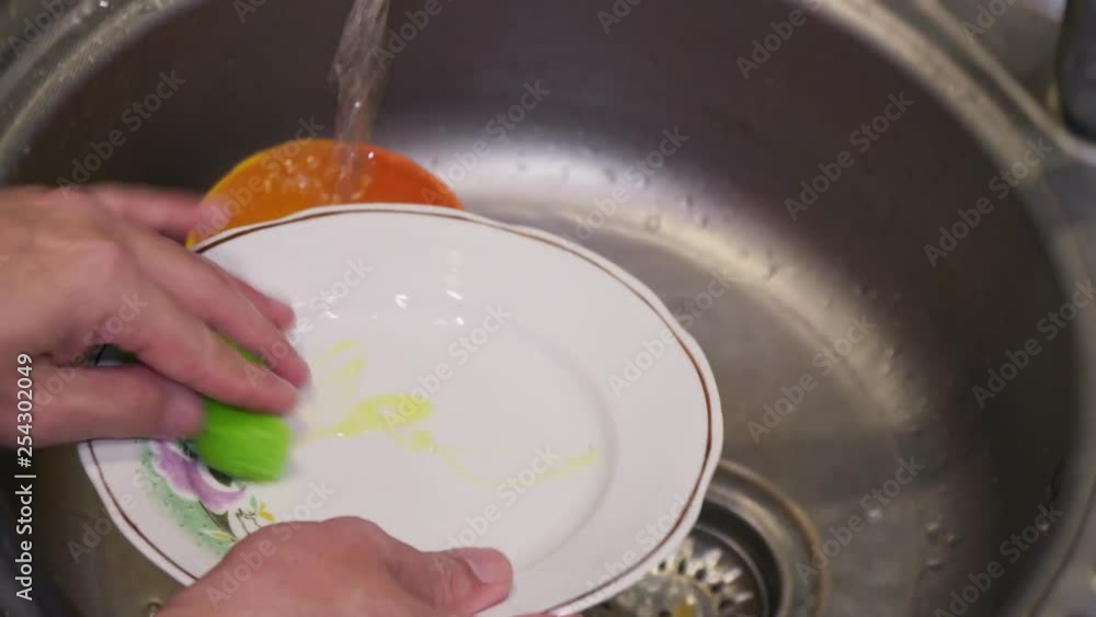 A large plate is washed in the sink with detergent close up A large plate is washed in the sink with detergent close up