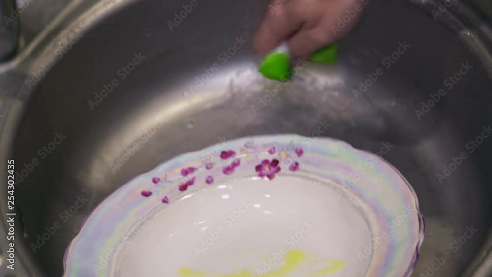 A plate is washed in the sink with detergent close up A plate is washed in the sink with detergent close up