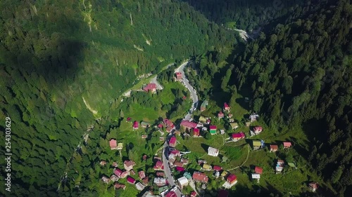 4K aerial bird look drone shot in slow motion, flying over Ayder Plateau, authentic settling between green epic mountains, sunny weather, in Ayder Highland, Rize Province, Turkey photo