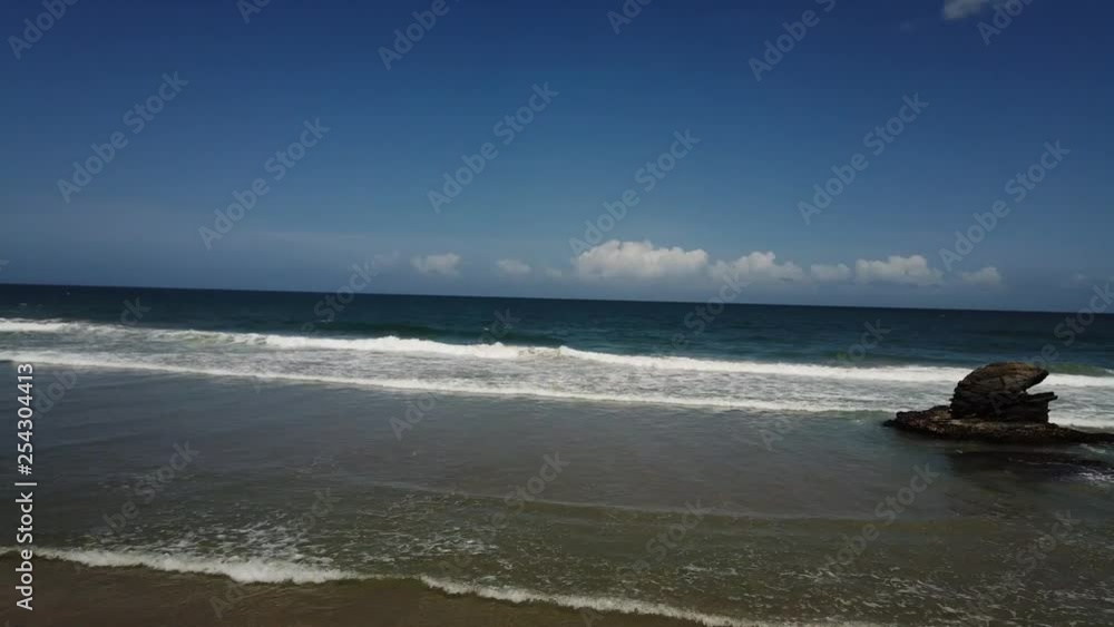 A motion time-lapse of a beach with rocks and clouds in the background A motion time-lapse of a beach with rocks and clouds in the background