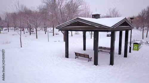 Wallpaper Mural Cinematic drone / aerial footage circling an open hut in a park over a snowy landscape, frozen lake, pathway and dry trees during winter season. Torontodigital.ca