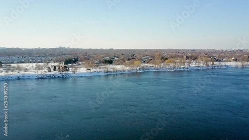 Wallpaper Mural Cinematic drone / aerial footage moving forwards over the lake showing a snowy landscape, pathway, houses, cars and dry trees during winter season. Torontodigital.ca