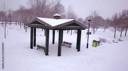 Wallpaper Mural Cinematic drone / aerial footage circling an open hut in a park over a snowy landscape, frozen lake, pathway and dry trees during winter season. Torontodigital.ca