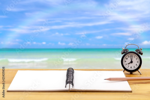 Alarm clock with notebook on sea background,this image for relaxing concept,soft focus.