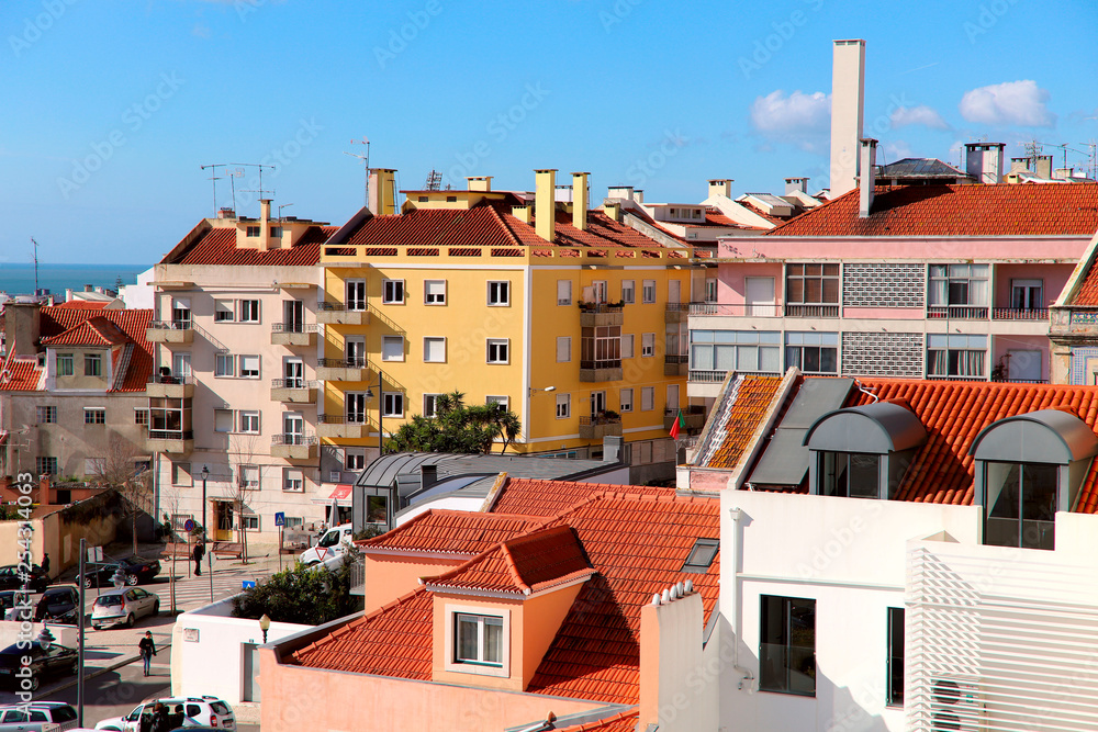 Side view of the bright old residential buildings with orange tiled roofs against the blue sky.Portugal, Lisbon. Cropped shot, horizontal. The concept of construction and tradition.
