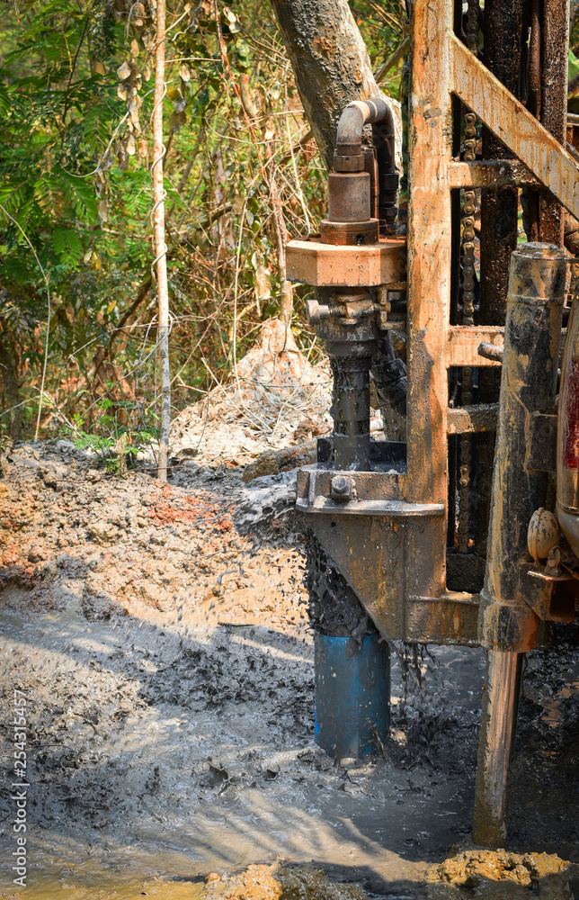Fototapeta premium Digging hole drilling groundwater machine installed on deeps ground soil and mud