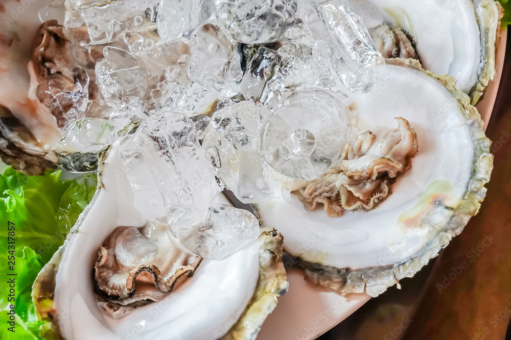 Close up fresh raw open oysters on plate served with ice, Thai style, top view.. Close up fresh raw open oysters on plate served with ice, Thai style, top view..