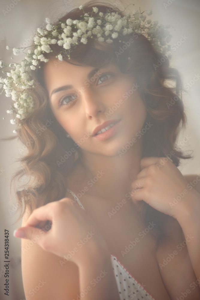 Young beautiful smiling woman in wreath of white flowers