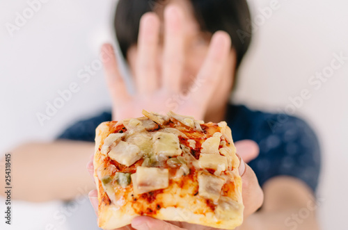 Young man rejecting pizza or unhealthy food. Dieting or good health concept. Unhealthy Eating Concept.