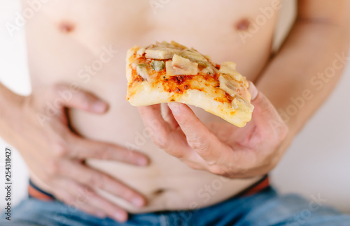 Close up half-length portrait of young fat man with holding pizza and enjoy eatting.Isolated on white background.Unhealthy concept..