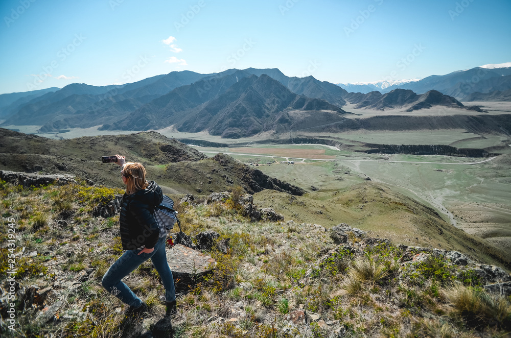 Fototapeta premium Girl tourist photographs mountain scenery. Selfies in the Altai Mountains. Chui tract, Altai. Valley Chuya.