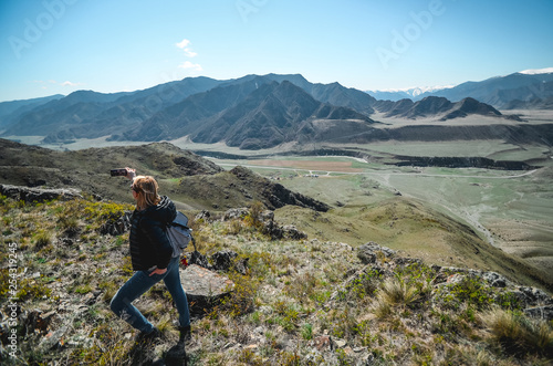 Girl tourist photographs mountain scenery. Selfies in the Altai Mountains. Chui tract, Altai. Valley Chuya.