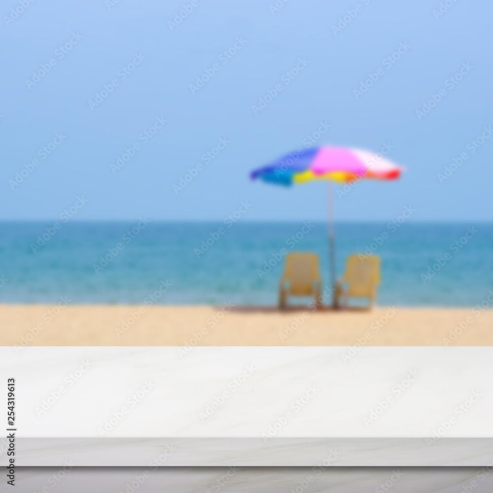 Empty white marble table over blur blue sky and sea beach with colorful umbrella in summer background, product display montage background, banner