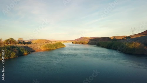 Drone flying alongside the all American Canal during sunset, Powerlines on the right side