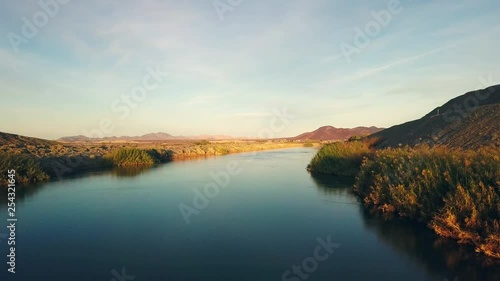 Aerial dolly, over the all American Canal during sunset, flying low showing the vegetation.
