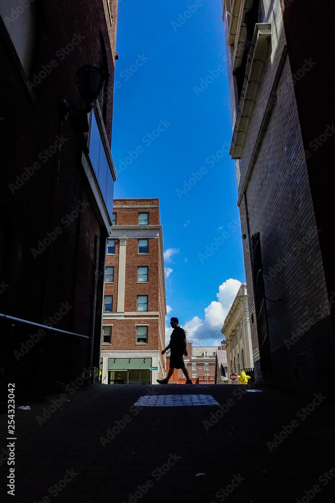 Obraz premium Pittsfield, Massachusetts, USA A man walking on North street is silhouetted in back alley.