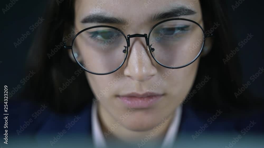 Young beautiful businesswoman sitting at a table with a laptop. In the evening, a female freelancer works remotely. Online training courses, reading books, watching videos online. Young beautiful businesswoman sitting at a table with a laptop. In the evening, a female freelancer works remotely. Online training courses, reading books, watching videos online.