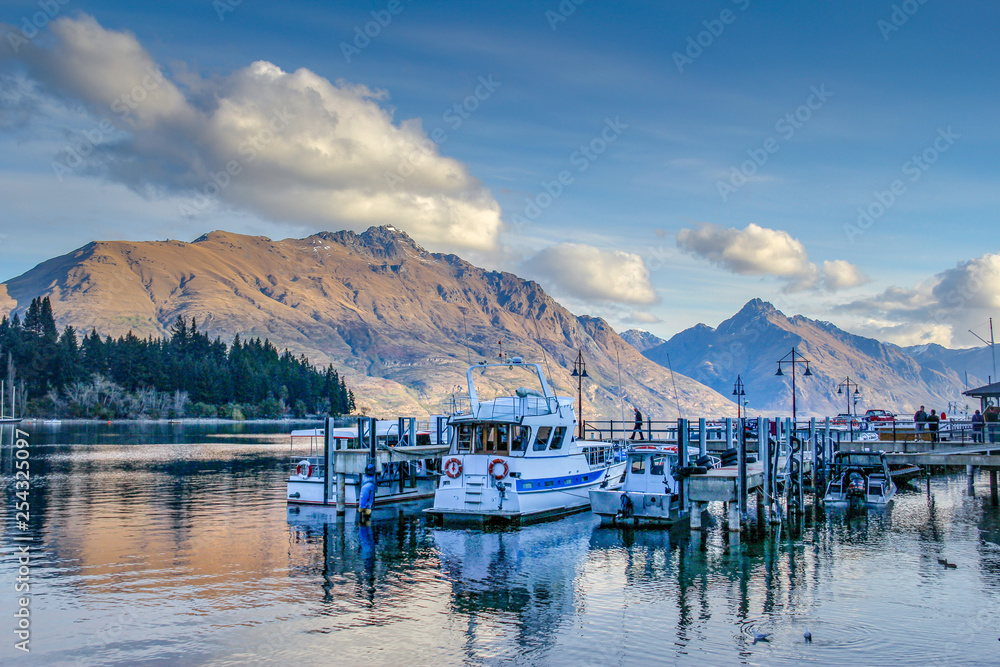 boats in the bay on a lake with mountains in queenstown south island new zealand